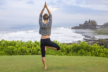 Indonesien, Bali, Tanah Lot, Frau übt Yoga an der Küste - KNTF000186