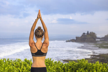 Indonesia, Bali, Tanah Lot, woman practising yoga at the coast - KNTF000187