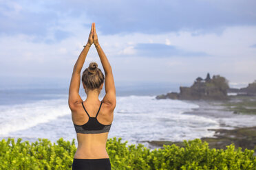Indonesien, Bali, Tanah Lot, Frau übt Yoga an der Küste - KNTF000187