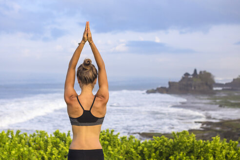 Indonesien, Bali, Tanah Lot, Frau übt Yoga an der Küste - KNTF000187