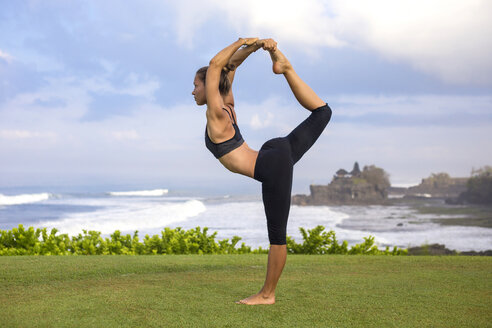 Indonesien, Bali, Tanah Lot, Frau übt Yoga an der Küste - KNTF000189