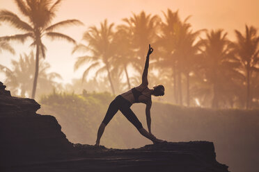 Indonesien, Bali, Frau übt Yoga an der Küste in der Dämmerung - KNTF000194