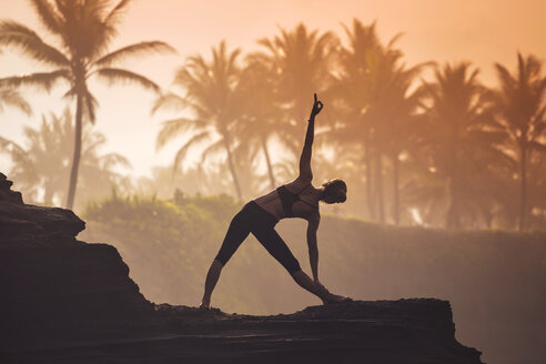 Indonesia, Bali, woman practising yoga at the coast at twilight - KNTF000194