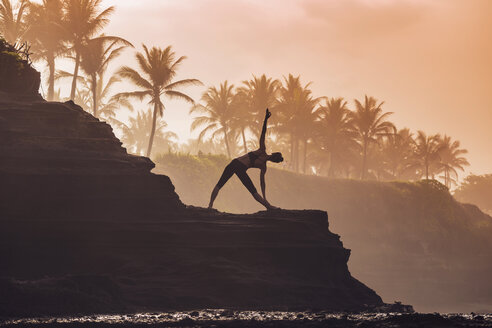 Indonesia, Bali, woman practising yoga at the coast at twilight - KNTF000195