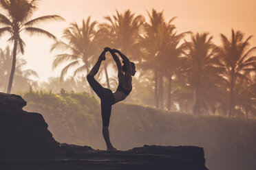 Indonesien, Bali, Frau übt Yoga an der Küste in der Dämmerung - KNTF000196