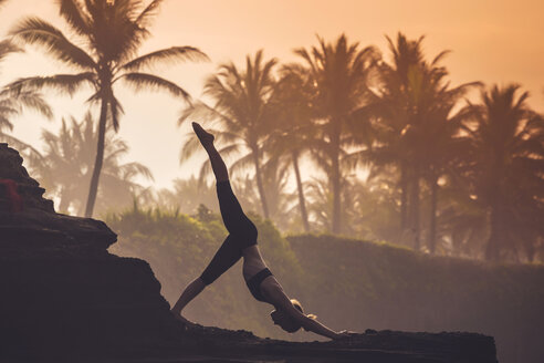 Indonesien, Bali, Frau übt Yoga an der Küste in der Dämmerung - KNTF000197