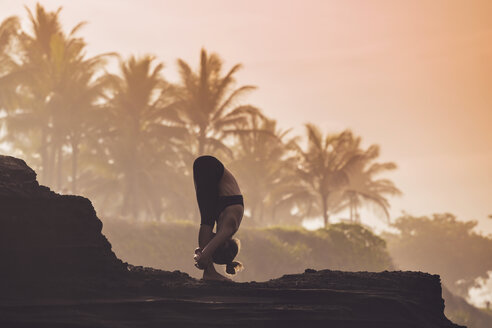 Indonesien, Bali, Frau übt Yoga an der Küste in der Dämmerung - KNTF000198