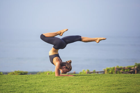 Indonesien, Bali, Frau übt Yoga auf Rasen - KNTF000200