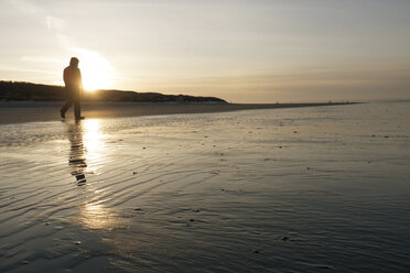 Deutschland, Insel Langeoog, Mann geht bei Sonnenuntergang am Strand spazieren - JATF000789