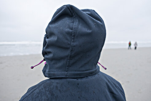 Deutschland, Insel Langeoog, Person mit nasser Kapuze am Strand - JATF000790