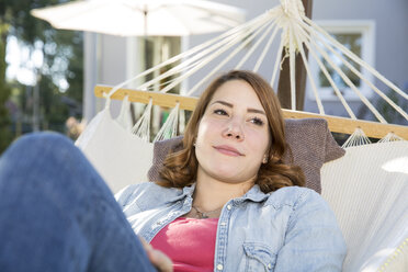 Young woman relaxing in hammock in garden - FKF001654