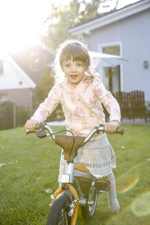 Mädchen auf Fahrrad im Garten - FKF001657