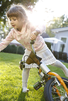 Mädchen auf Fahrrad im Garten - FKF001659