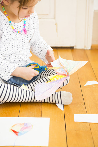 Kleines Mädchen bastelt mit Papier und Schere, lizenzfreies Stockfoto