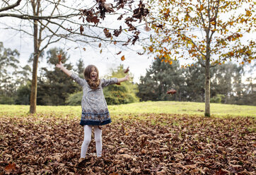Lachendes Mädchen wirft Herbstblätter in die Luft - MGOF001112