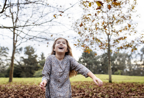 Glückliches Mädchen wirft Herbstblätter in die Luft, lizenzfreies Stockfoto