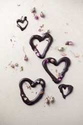 Schokoladenherzen und getrocknete Rosenblüten auf hellem Grund - MYF001256