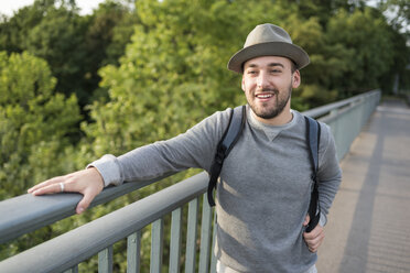 Porträt eines bärtigen jungen Mannes mit Hut, der auf einer Brücke steht - PAF001496