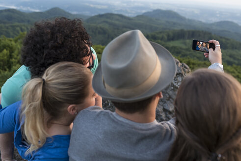 Deutschland, Siebengebirge, Rückenansicht von vier Freunden, die ein Selfie mit Smartphone auf dem Ölberg machen - PAF001501