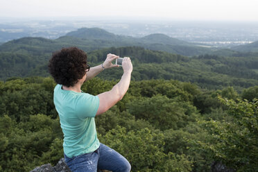 Deutschland, Siebengebirge, Mann fotografiert Aussicht mit Smartphone auf dem Ölberg - PAF001502