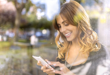 Portrait of happy young woman looking at her smartphone - MGOF001129