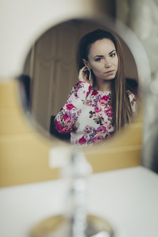 Reflection of young woman in floral dress in mirror stock photo