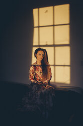 Young woman in floral dress in sunlight in a room - MAUF000125