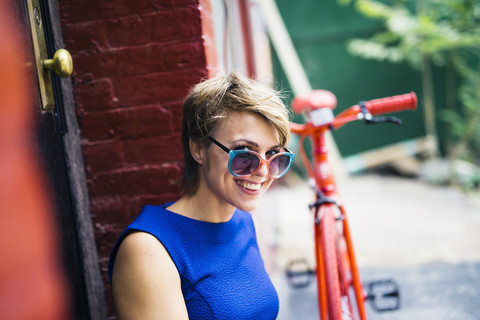 Porträt einer lächelnden blonden Frau mit Sonnenbrille auf der Nasenspitze, lizenzfreies Stockfoto