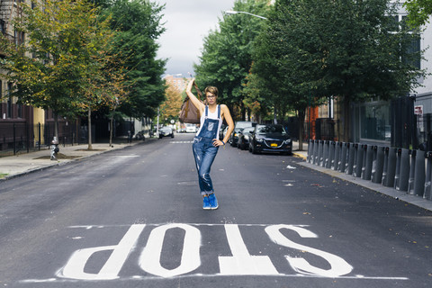 USA, New York City, Williamsburg, Frau in Jeans-Latzhose posiert auf der Straße, lizenzfreies Stockfoto