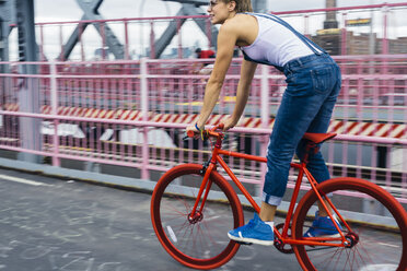 USA, New York City, Williamsburg, woman riding red racing cycle on Williamsburg Bridge - GIOF000582