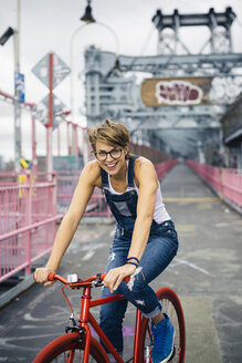 USA, New York City, Williamsburg, Porträt einer blonden Frau mit rotem Rennrad auf der Williamsburg Bridge - GIOF000583