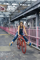 USA, New York City, Williamsburg, woman with red racing cycle on Williamsburg Bridge - GIOF000584