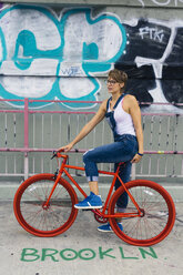 USA, New York City, Williamsburg, blond woman with red racing cycle on Williamsburg Bridge - GIOF000587