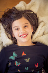 Portrait of smiling girl lying on blanket on the floor - LVF004229