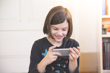 Portrait of smiling girl looking at smartphone - LVF004233