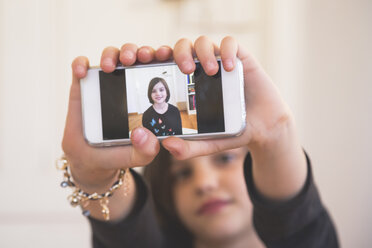 Hands of girl showing smartphone with photography of herself - LVF004236