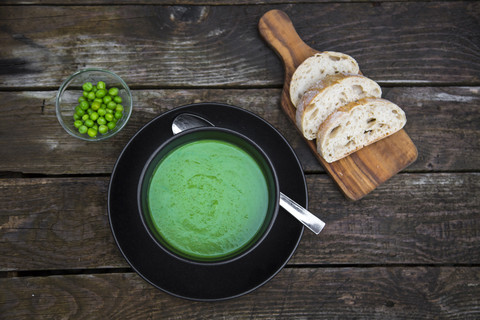 Schüssel mit Erbsensuppe, Weißbrot auf dem Schneidebrett, lizenzfreies Stockfoto