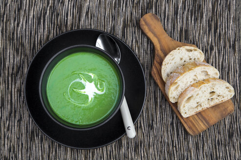 Schüssel mit Erbsensuppe, Weißbrot auf dem Schneidebrett - SARF002369