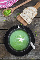 Bowl of pea soup, white bread on chopping board - SARF002370