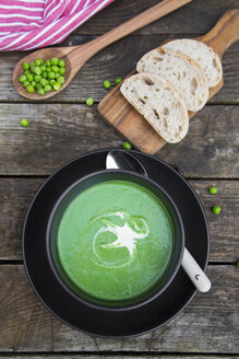 Schüssel mit Erbsensuppe, Weißbrot auf dem Schneidebrett - SARF002370