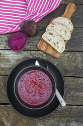 Bowl of beetroot soup, white bread on chopping board - SARF002371