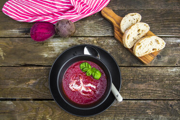 Bowl of beetroot soup, white bread on chopping board - SARF002372