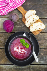 Bowl of beetroot soup, white bread on chopping board - SARF002373