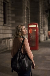 UK, London, young woman taking a walk in the evening - MAUF000139