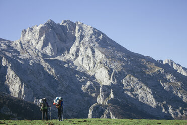 Spain, Picos de Europa, two hikers with mountains landscape in the background - ABZF000157
