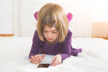 Kleines Mädchen mit Smartphone auf einer Decke auf dem Boden liegend - LVF004245