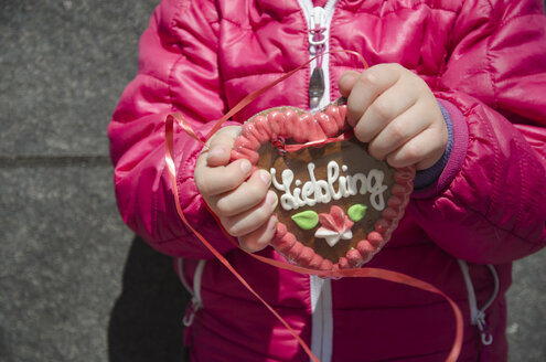 Girl holding gingerbread heart with German inscription - GSF001013