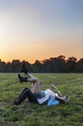 Glückliches verliebtes Paar auf einer Wiese bei Sonnenuntergang liegend - BOYF000010