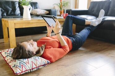 Junge Frau auf dem Boden ihres Wohnzimmers mit digitalem Tablet liegend - BOYF000021