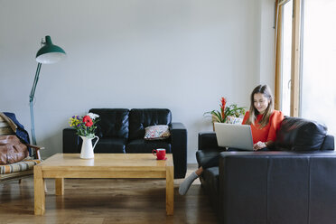 Young woman with laptop relaxing on the couch in her living room - BOYF000024